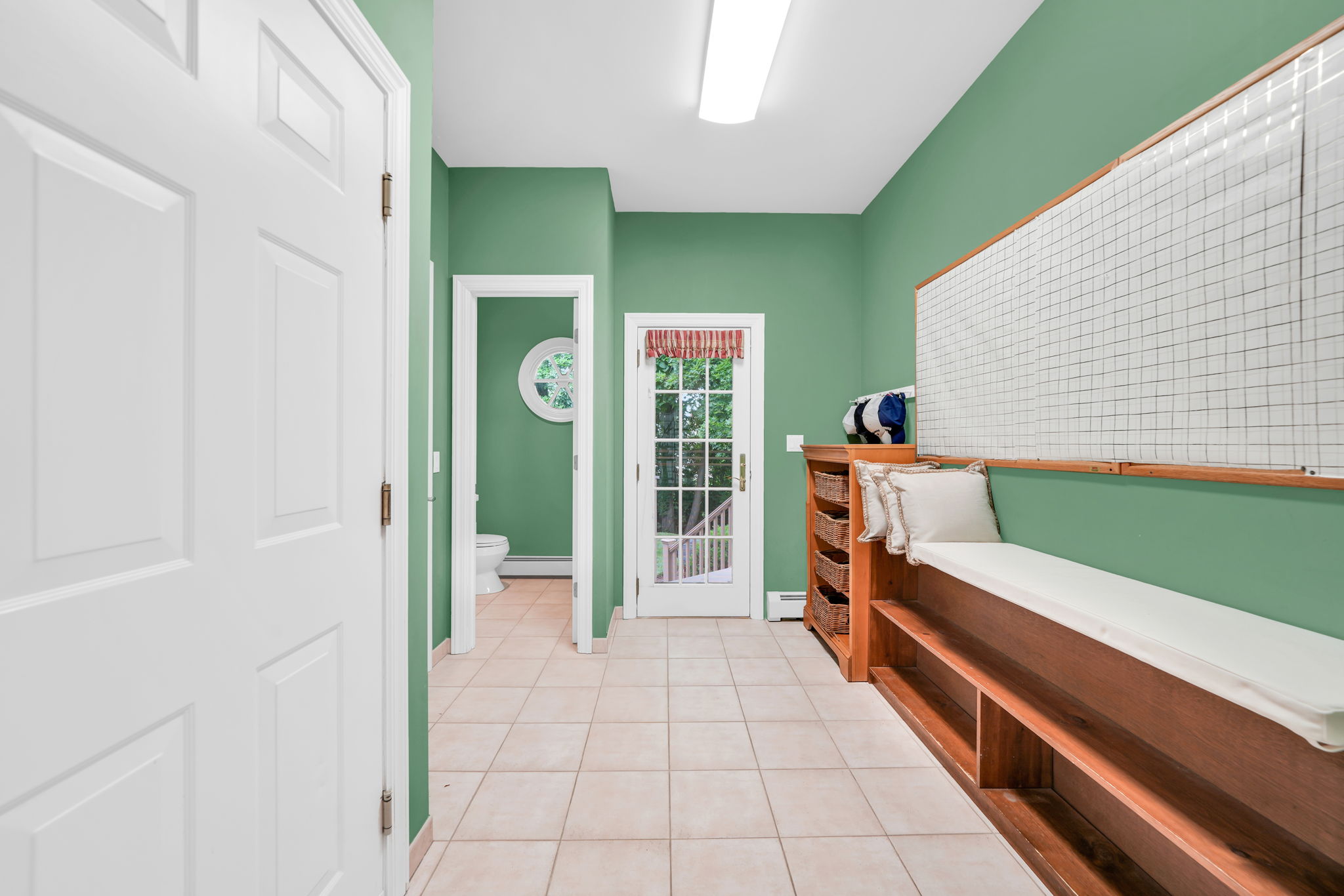 Just beyond, a landing off the second staircase holds a true mudroom, complete with built-in bench seating, cubby storage, and a coat closet, a powder room tucked neatly away, and direct access to the garage.