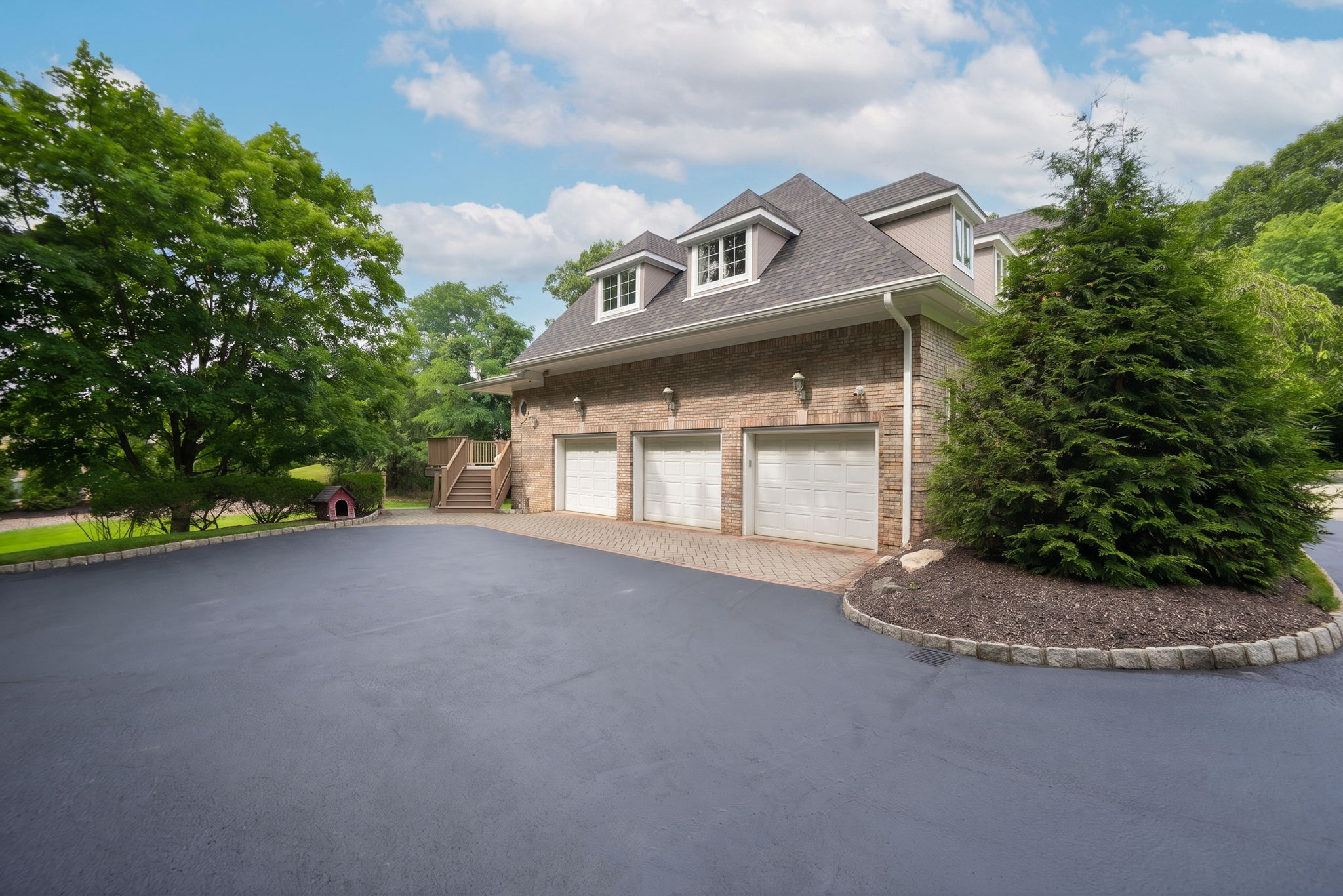 The approach alone tells you what you're in for. A circular driveway, anchored by a paver walkway at its center, sweeps past manicured grounds toward an oversized three-car garage and an entrance built for arrival, framed by brick on three sides of the home's exterior.