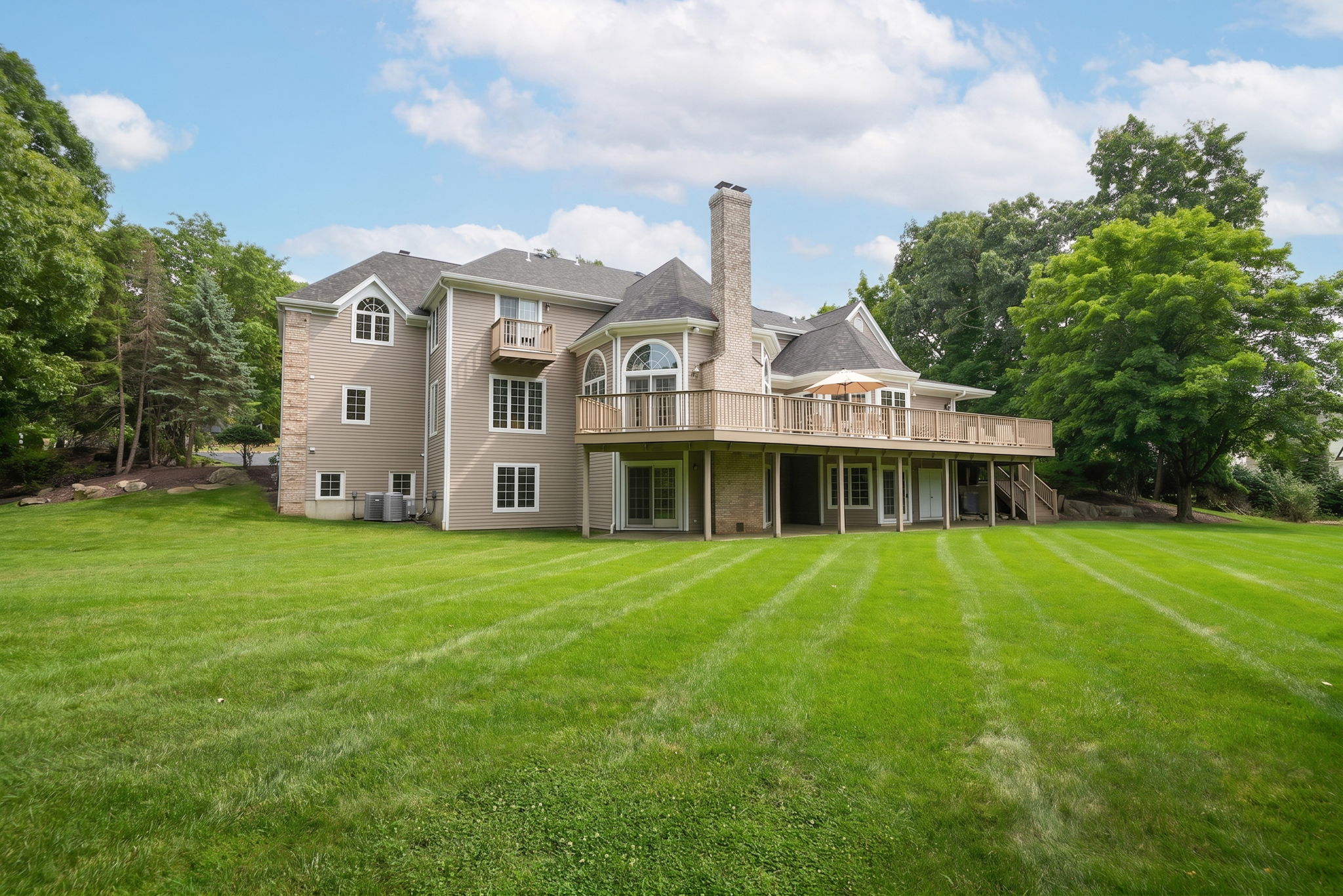 Downstairs, the fully finished and furnished walk-out lower level is built for entertaining, anchored by its own family room warmed by a stone fireplace, oversized windows that flood the space with natural light, French doors leading to a covered patio and the flat, grassy backyard beyond, and its own separate entrance from the garage in addition to access from the main living areas.