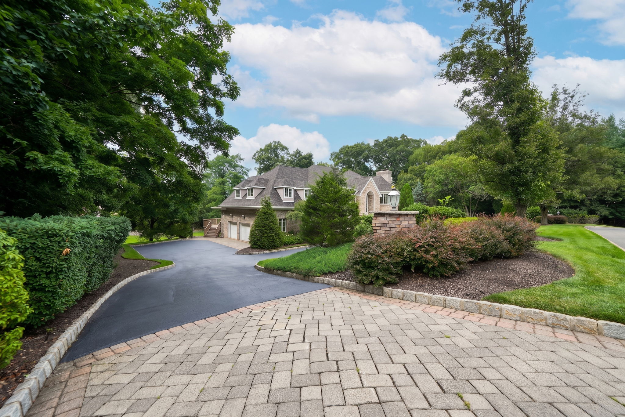 The approach alone tells you what you're in for. A circular driveway, anchored by a paver walkway at its center, sweeps past manicured grounds toward an oversized three-car garage and an entrance built for arrival, framed by brick on three sides of the home's exterior.