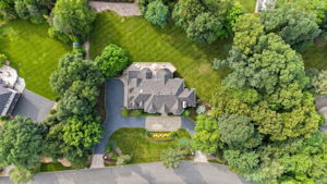 The approach alone tells you what you're in for. A circular driveway, anchored by a paver walkway at its center, sweeps past manicured grounds toward an oversized three-car garage and an entrance built for arrival, framed by brick on three sides of the home's exterior.