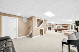 Downstairs, the fully finished and furnished walk-out lower level is built for entertaining, anchored by its own family room warmed by a stone fireplace, oversized windows that flood the space with natural light, French doors leading to a covered patio and the flat, grassy backyard beyond, and its own separate entrance from the garage in addition to access from the main living areas.