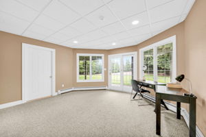 Downstairs, the fully finished and furnished walk-out lower level is built for entertaining, anchored by its own family room warmed by a stone fireplace, oversized windows that flood the space with natural light, French doors leading to a covered patio and the flat, grassy backyard beyond, and its own separate entrance from the garage in addition to access from the main living areas.