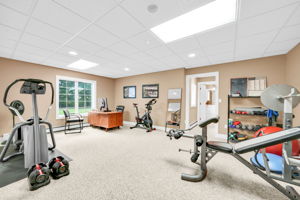A large room currently used as a home gym and second office, already fitted with an egress window, sits beside the home's sixth full bath, offering the potential to convert the space into a sixth guest suite