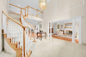 Step through the door into a two-story foyer, where a grand, cascading staircase rises beneath a wall of light