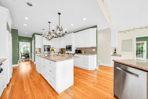 To the left, the kitchen: a bright, all-white showpiece with a large island for prepping or casual dining, an eat-in nook for everyday meals, a walk-in pantry, and a butler's pantry connecting seamlessly to the formal dining room. And just off the kitchen, in a detail only a homeowner who truly lived in the space would think to include, a second staircase with a wooden ladder rail, scaled for little hands and big hands alike, is tucked charmingly beside the everyday comings and goings of family life.