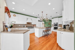 To the left, the kitchen: a bright, all-white showpiece with a large island for prepping or casual dining, an eat-in nook for everyday meals, a walk-in pantry, and a butler's pantry connecting seamlessly to the formal dining room. And just off the kitchen, in a detail only a homeowner who truly lived in the space would think to include, a second staircase with a wooden ladder rail, scaled for little hands and big hands alike, is tucked charmingly beside the everyday comings and goings of family life.