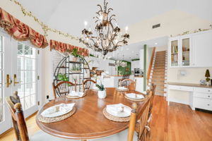 To the left, the kitchen: a bright, all-white showpiece with a large island for prepping or casual dining, an eat-in nook for everyday meals, a walk-in pantry, and a butler's pantry connecting seamlessly to the formal dining room. And just off the kitchen, in a detail only a homeowner who truly lived in the space would think to include, a second staircase with a wooden ladder rail, scaled for little hands and big hands alike, is tucked charmingly beside the everyday comings and goings of family life.