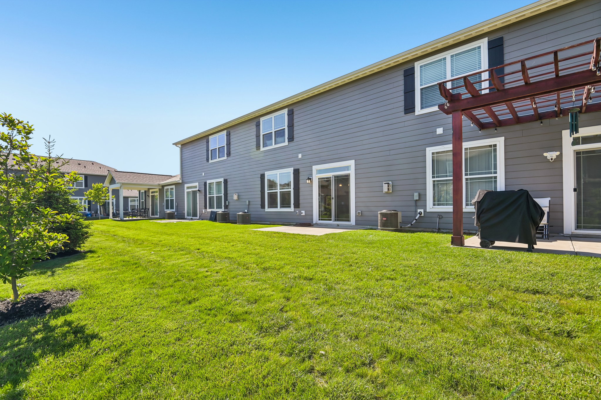 Open green space behind the property creates an airy and spacious feel.