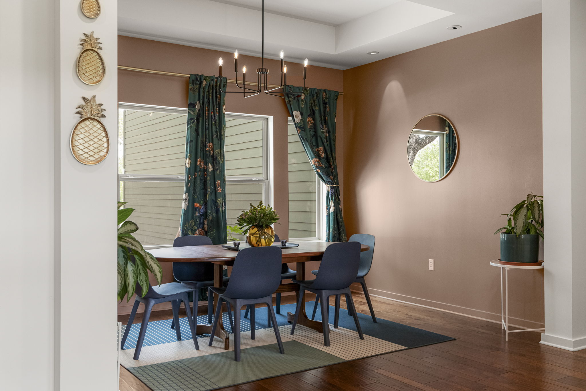 Large windows, sophisticated lighting, and thoughtfully selected window treatments create an inviting backdrop for gathering around the table.