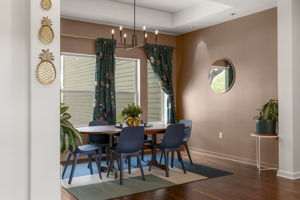Large windows, sophisticated lighting, and thoughtfully selected window treatments create an inviting backdrop for gathering around the table.