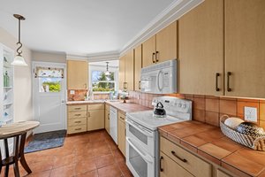 "This warm, welcoming kitchen boasts updated appliances and a sunlit corner window above the sink—perfect for daydreaming while you cook."