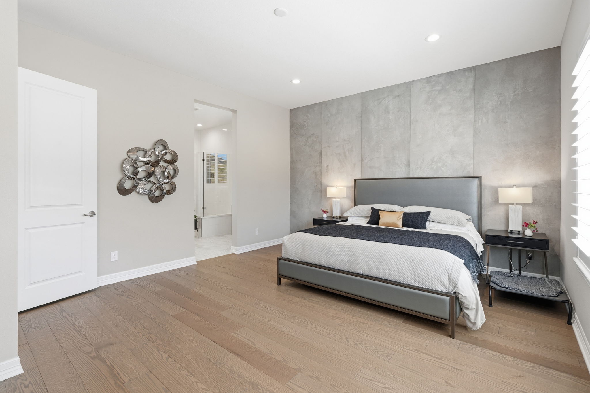 Spacious primary bedroom with custom concrete wall accent