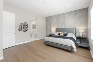 Spacious primary bedroom with custom concrete wall accent