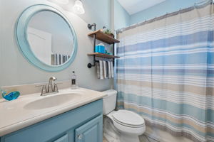 Second bathroom features tiled tub and shower combination.