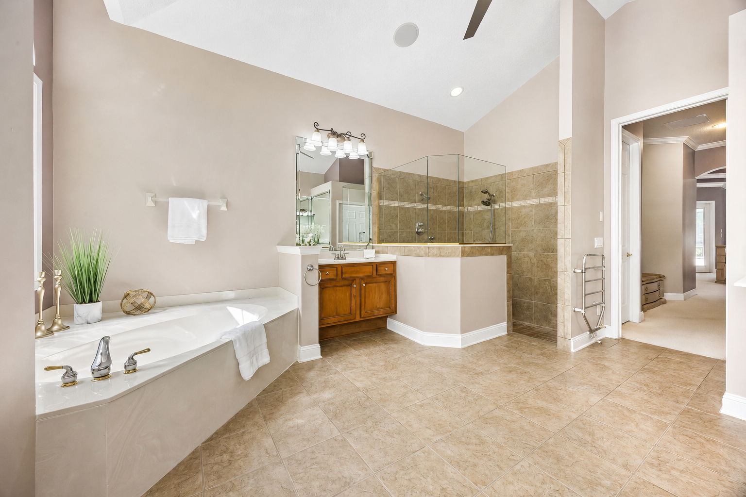 The primary bath is spacious and well arranged, with a soaking tub, glass-enclosed shower, and separate vanity areas ...
