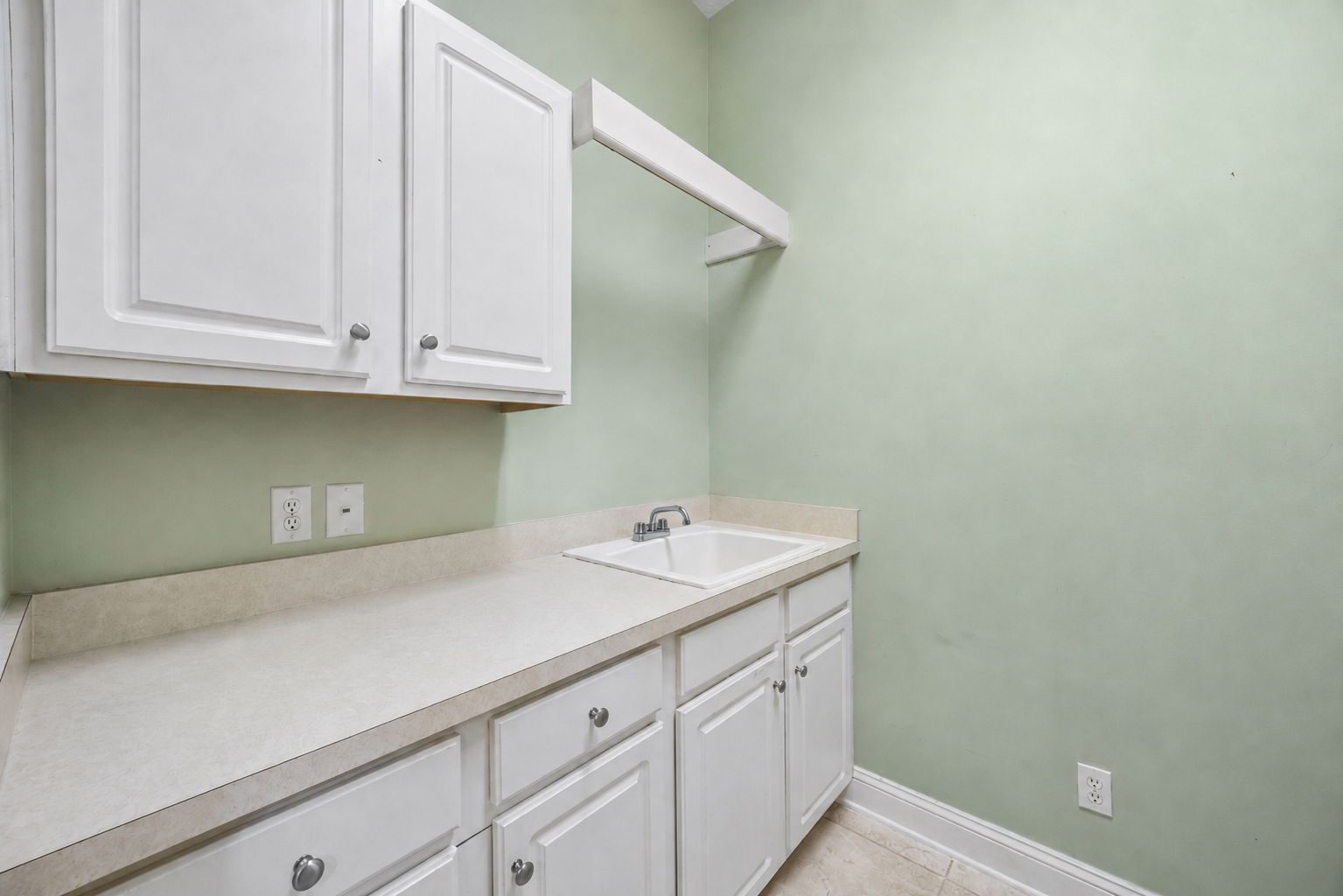 A well-appointed laundry room includes cabinetry, counter space, a utility sink ...