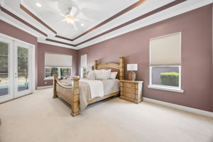 The primary suite feels calm and substantial, with direct pool access and a dramatic double tray ceiling ...