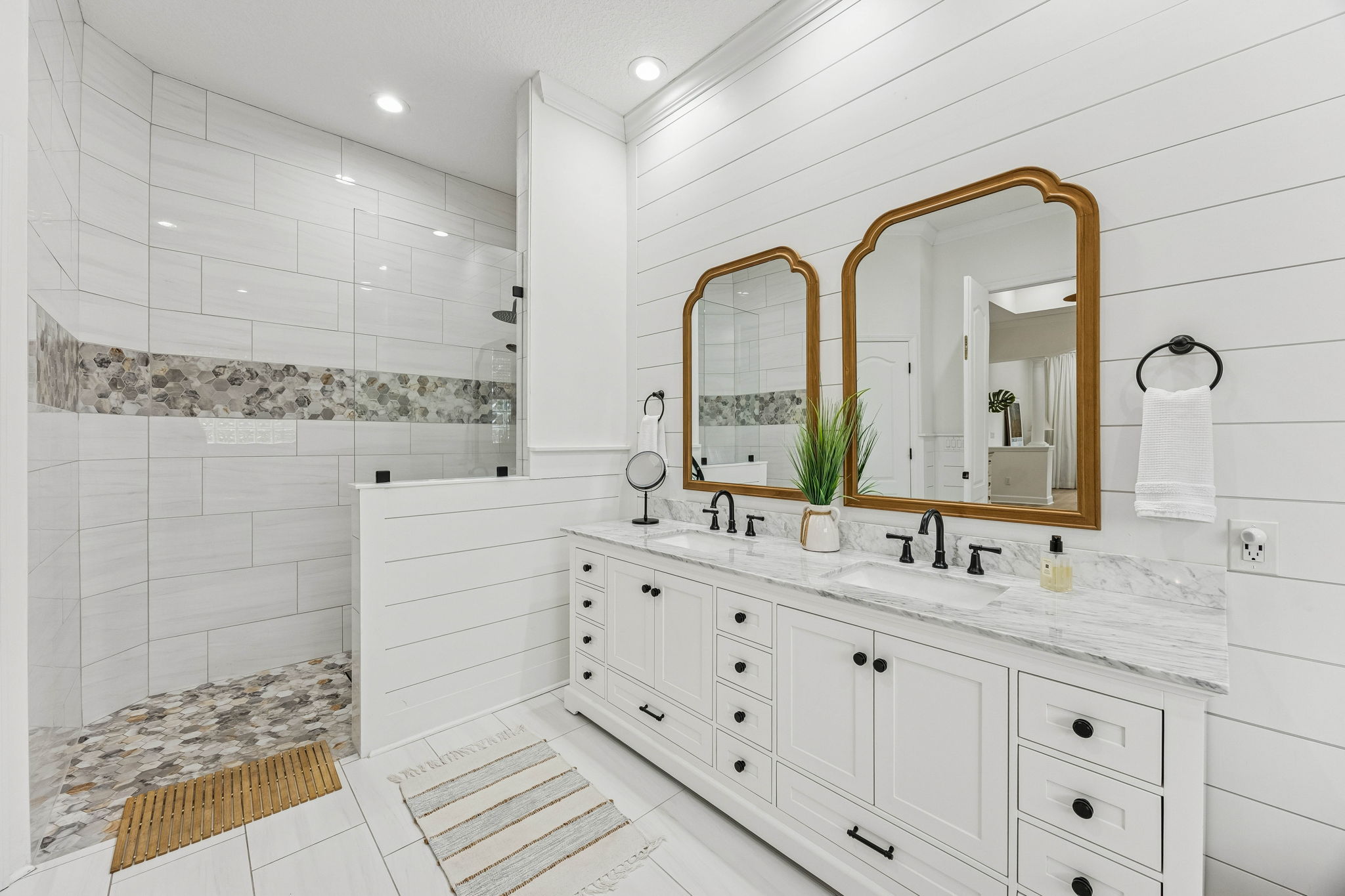 ... and custom dual vanities with quartz countertops, framed mirrors, and matte black fixtures