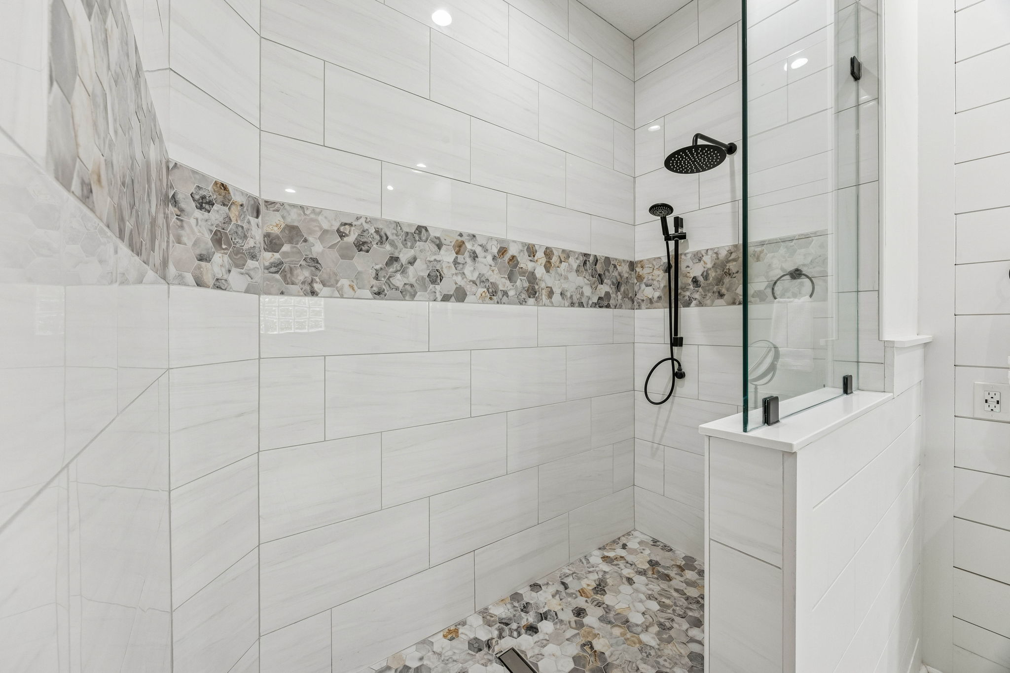 ... and finally, a walk-in shower with floor-to-ceiling tile, a designer stone accent band, and striking hex mosaic floor!