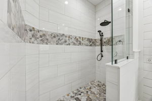 ... and finally, a walk-in shower with floor-to-ceiling tile, a designer stone accent band, and striking hex mosaic floor!