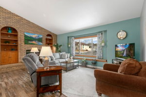 Lovely living room features a brick wall with fireplace and built-in shelving