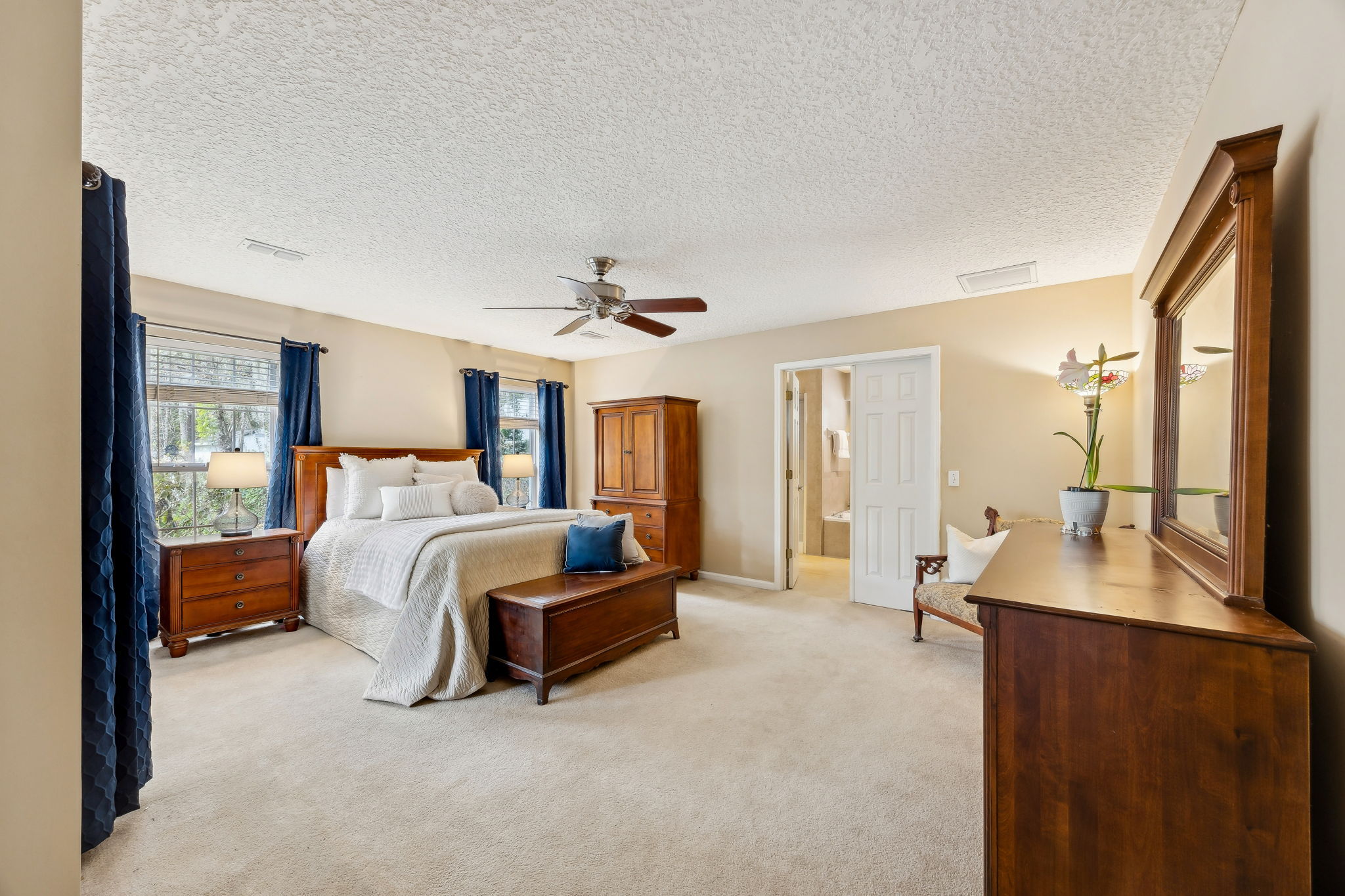 The primary bedroom is spacious, with three oversized windows filling the room with natural light.