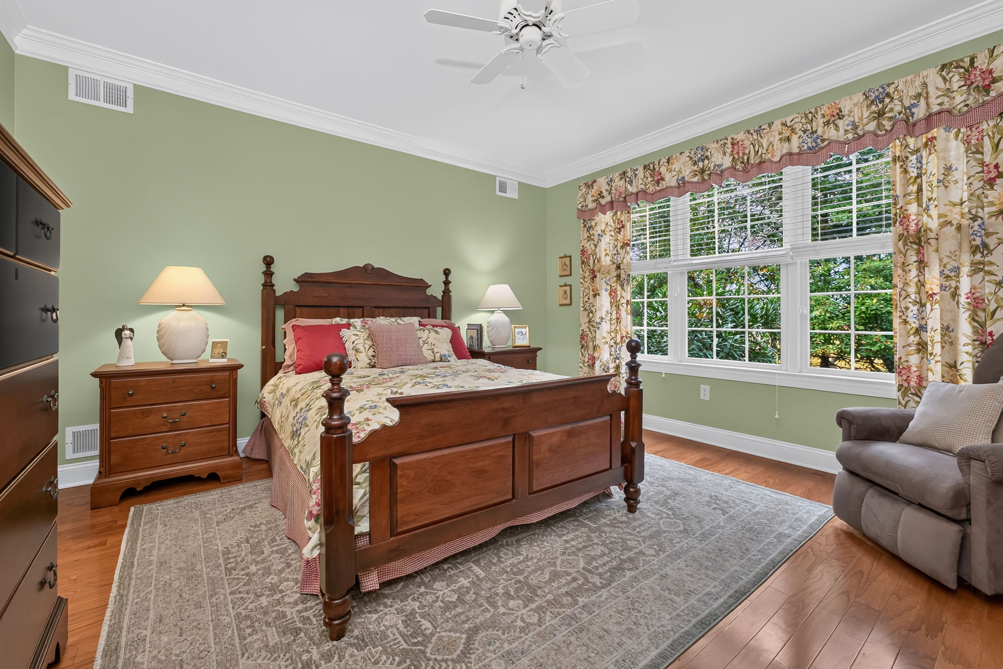 PRIMARY SUITE The first floor primary suite offers crown moulding, recessed lighting, a ceiling fan, walk-in closet and hardwood flooring.