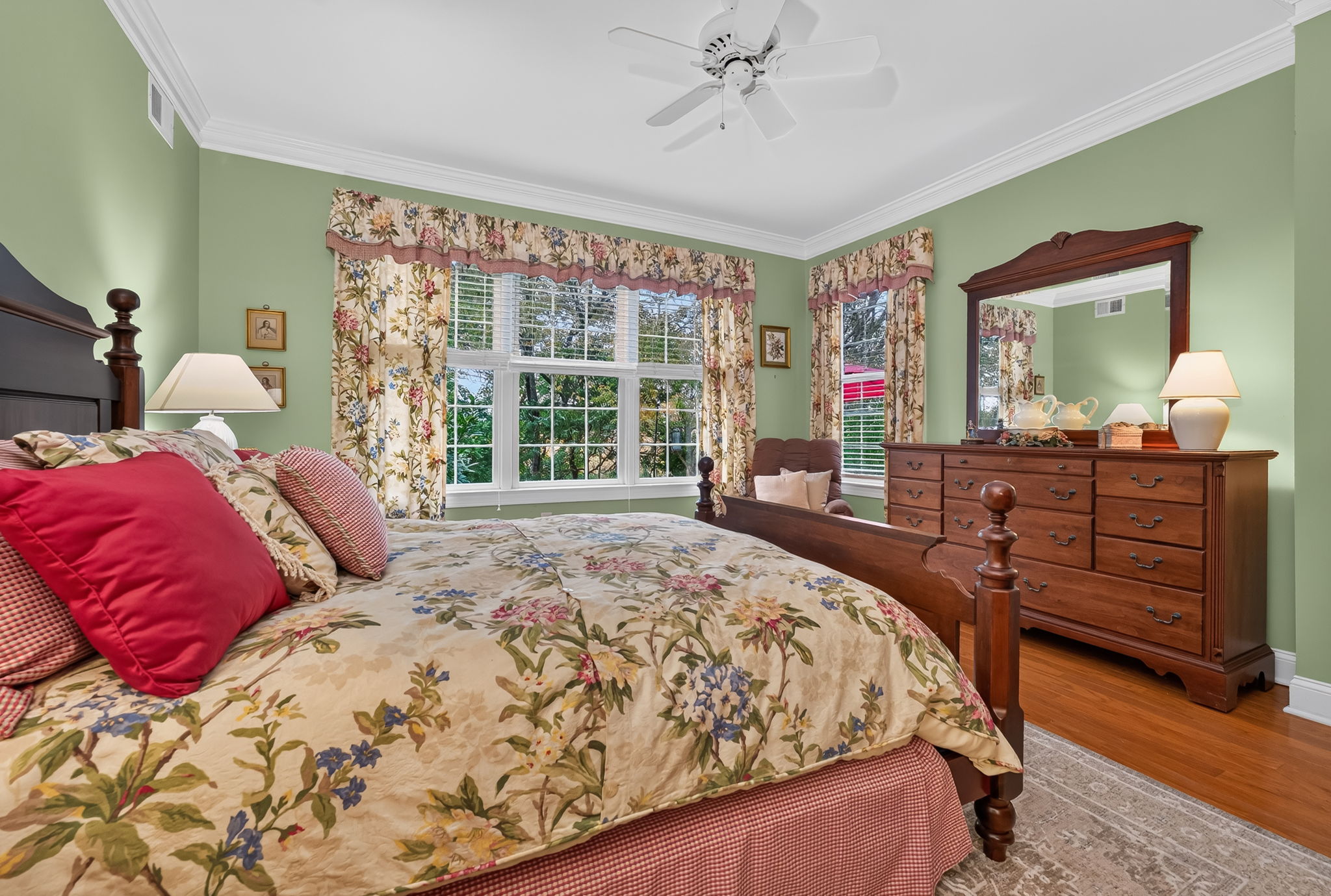 PRIMARY SUITE The first floor primary suite offers crown moulding, recessed lighting, a ceiling fan, walk-in closet and hardwood flooring.