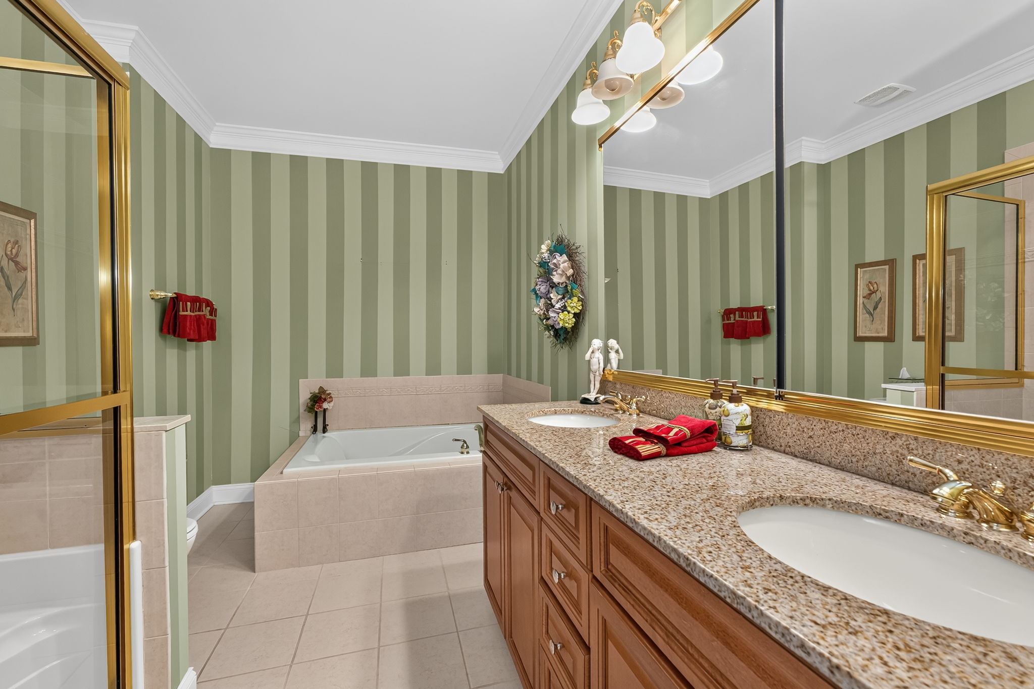 EN SUITE BATH Features of the private bath include an upgraded wood vanity with make up counter and double sinks, mirrored medicine cabinet, soaking tub, seated shower, and ceramic tile flooring.