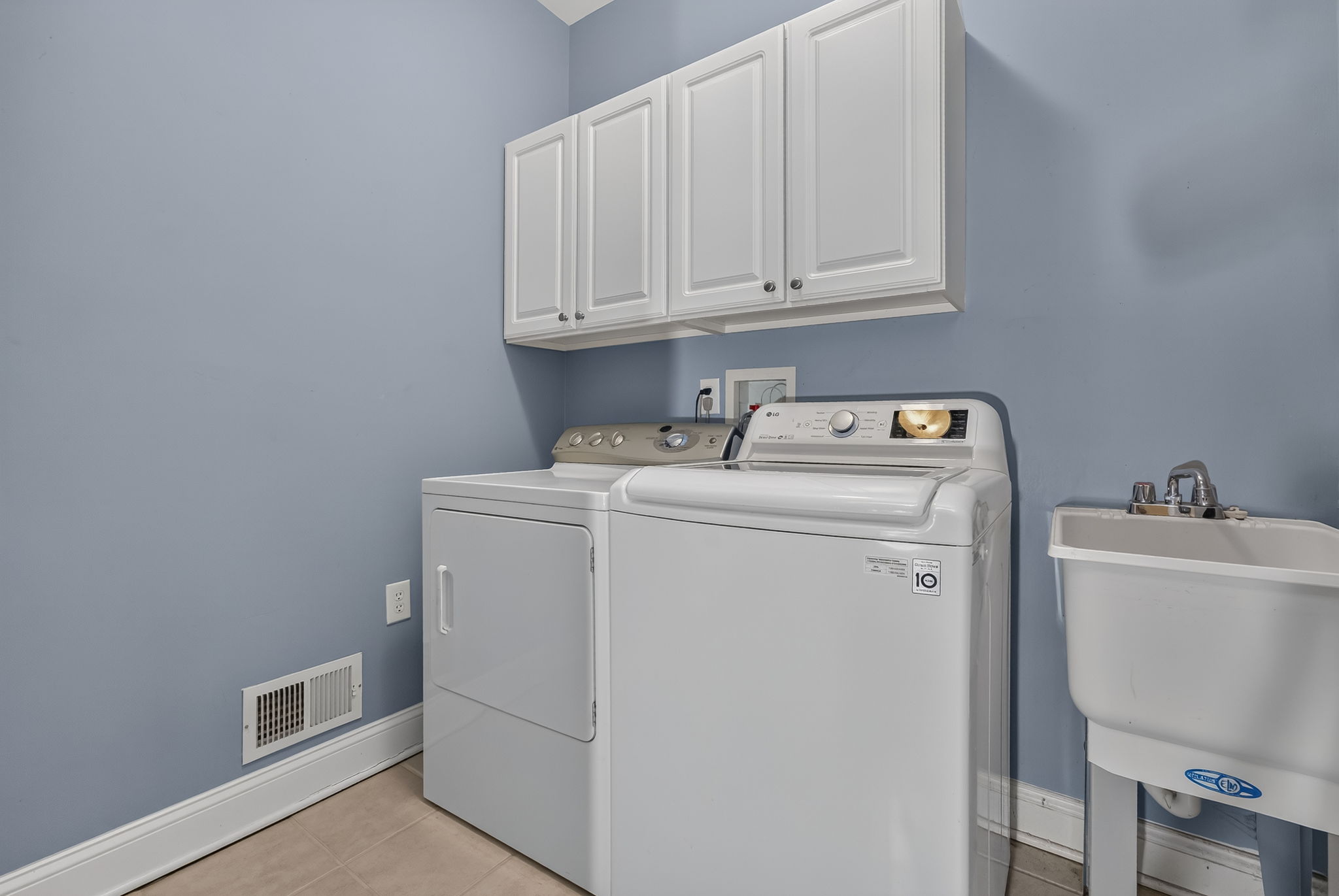 LAUNDRY ROOM Upper cabinets, utility sink, washer, and dryer.