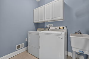 LAUNDRY ROOM Upper cabinets, utility sink, washer, and dryer.