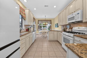 The eat-in kitchen is appointed with upgraded cabinetry, 42-inch upper cabinets, granite countertops, a tum-bled tile backsplash, and quality appliances.