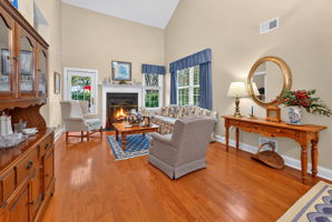 TWO STORY LIVING ROOM A French door opens to a paver patio overlooking a peaceful backdrop of mature trees and open green space.