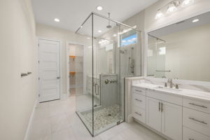 Primary Bathroom features dual vanities & frameless shower, walk-in closet