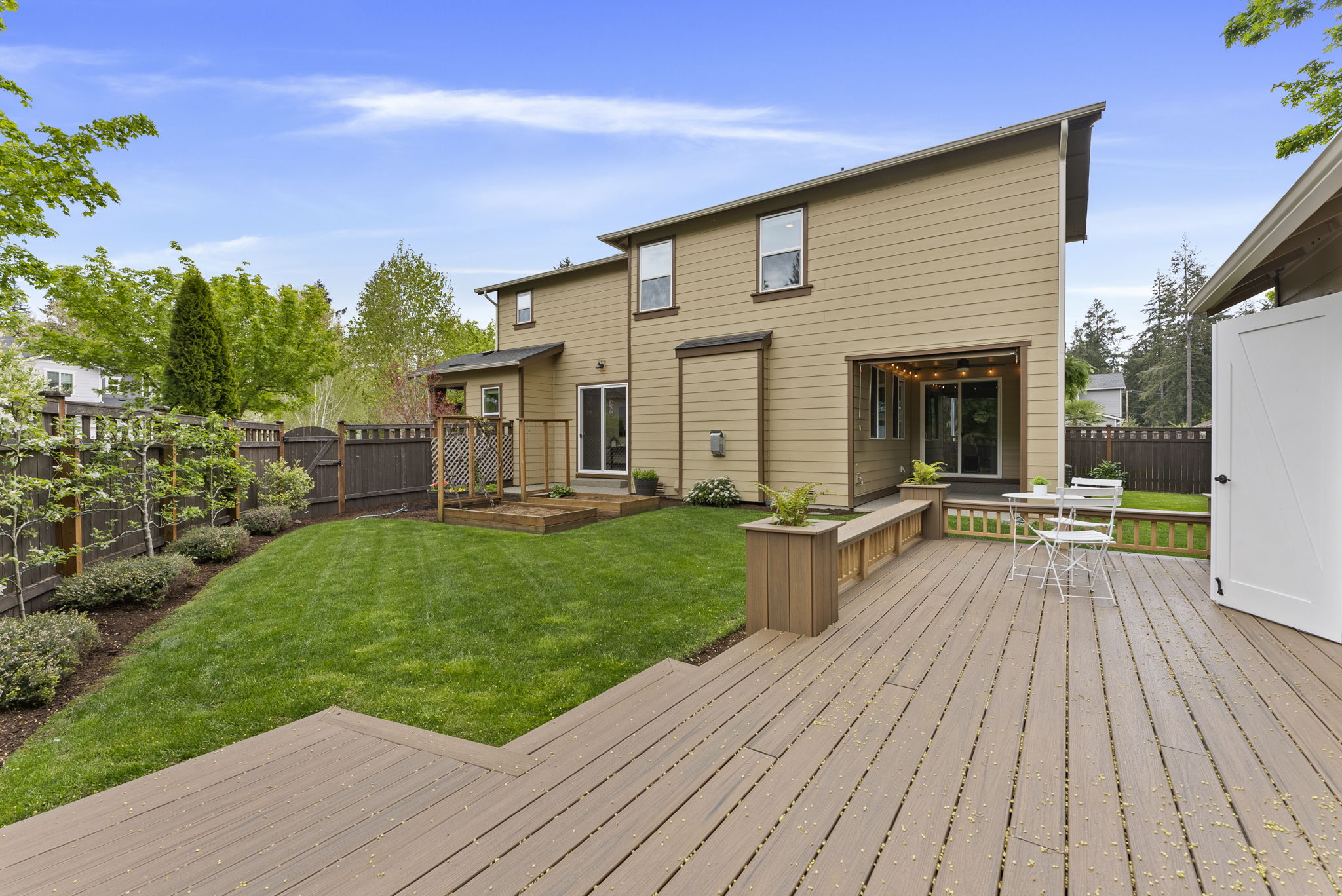Scenic views from the custom shop deck overlooking garden beds and thoughtfully planted apple trees and grapevines