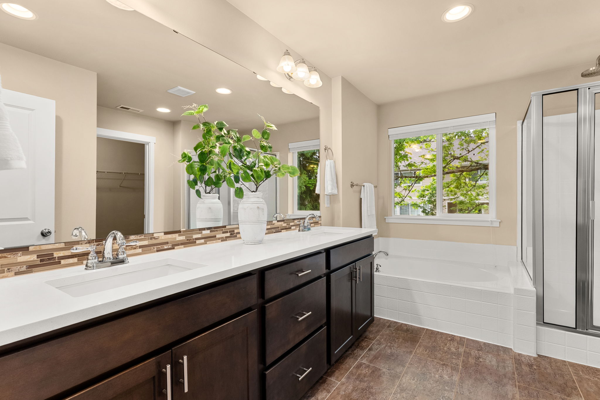 Primary bath featuring dual sinks and a soaking tub with backyard views