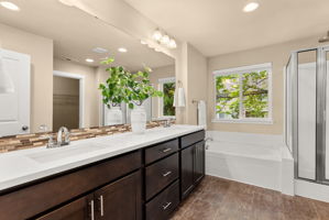 Primary bath featuring dual sinks and a soaking tub with backyard views