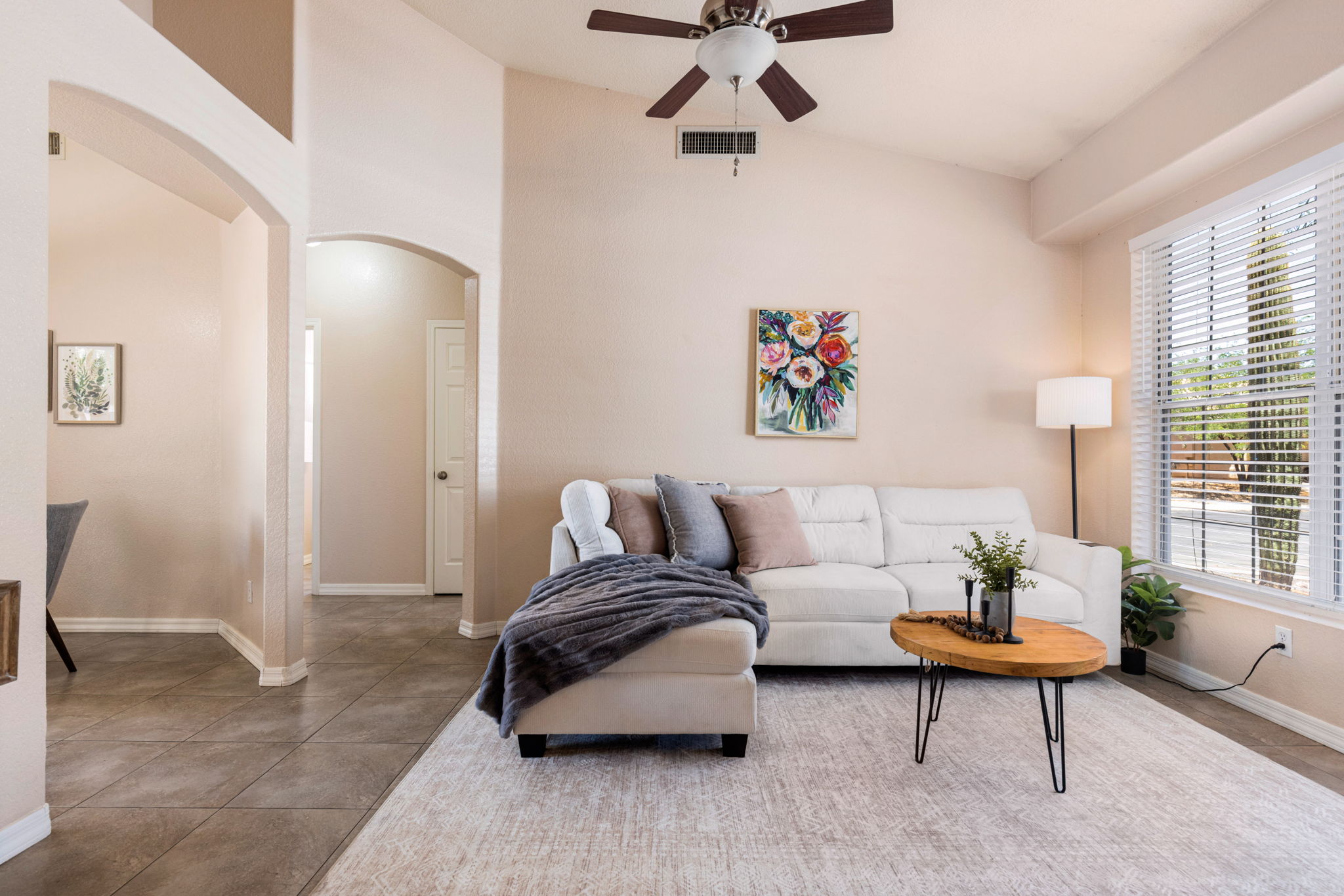 Inviting living room with vaulted ceilings and neutral ceramic tile throughout the whole home.