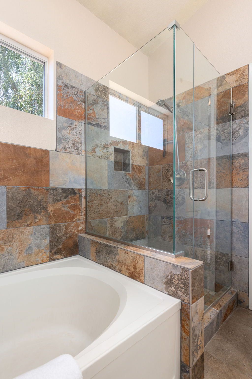 Slate tiled walk in shower with glass doors.