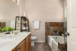 Double sink vanity and soaking tub surrounded by stylist slate.
