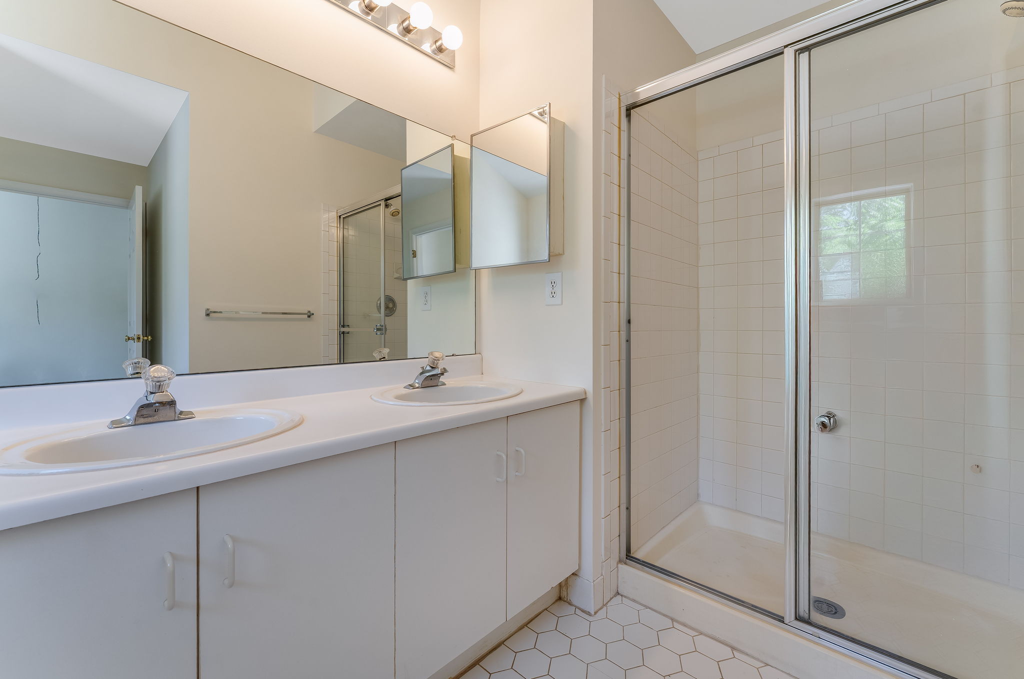 The en suite bath offers a high ceiling, double basins in white vanity, soaking tub and shower in tile surround, ceramic tile floor.