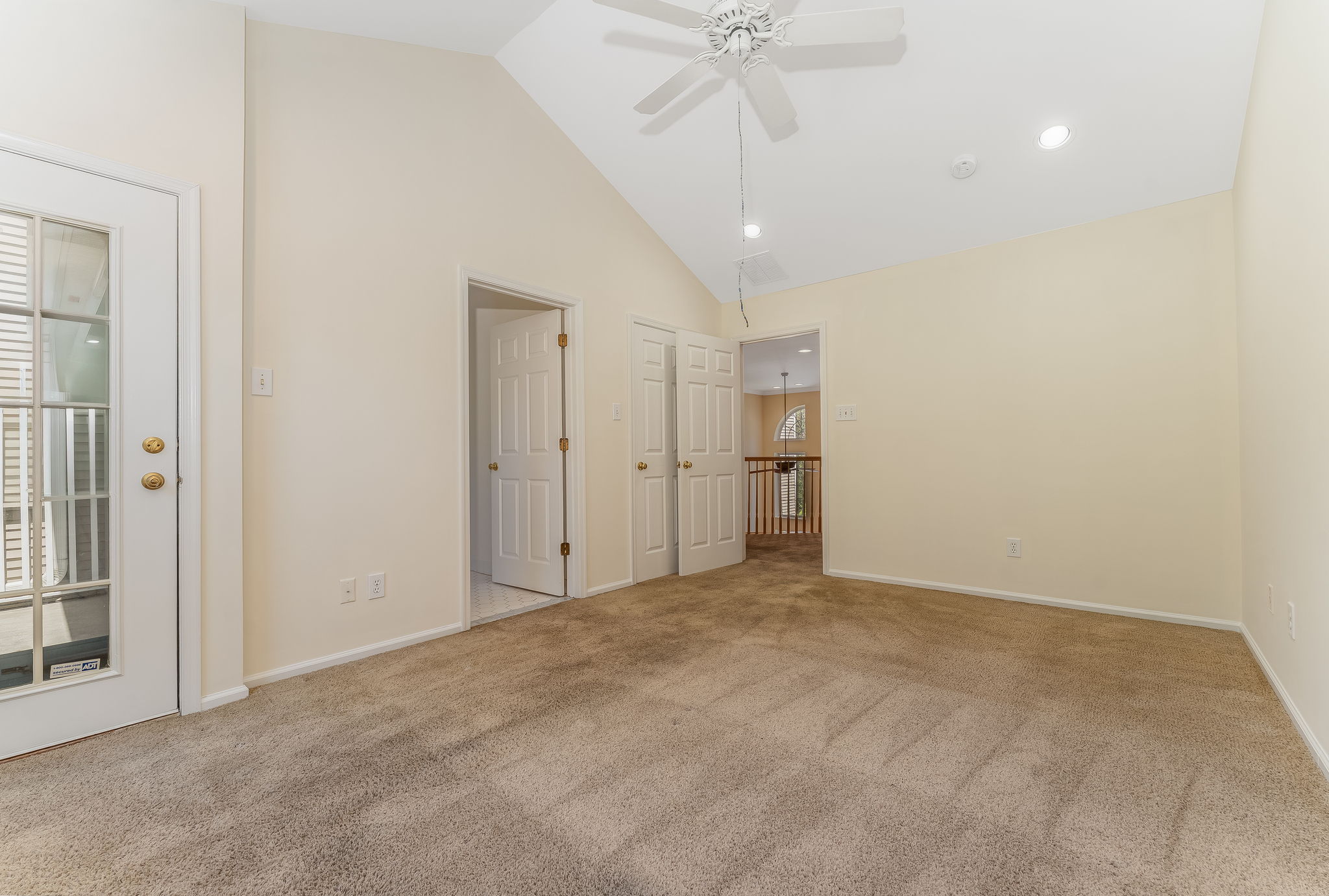 The primary bedroom features a cathedral ceiling, recessed lighting, ceiling fan, walk-in closet, and neutral carpeting, with direct access to a private deck