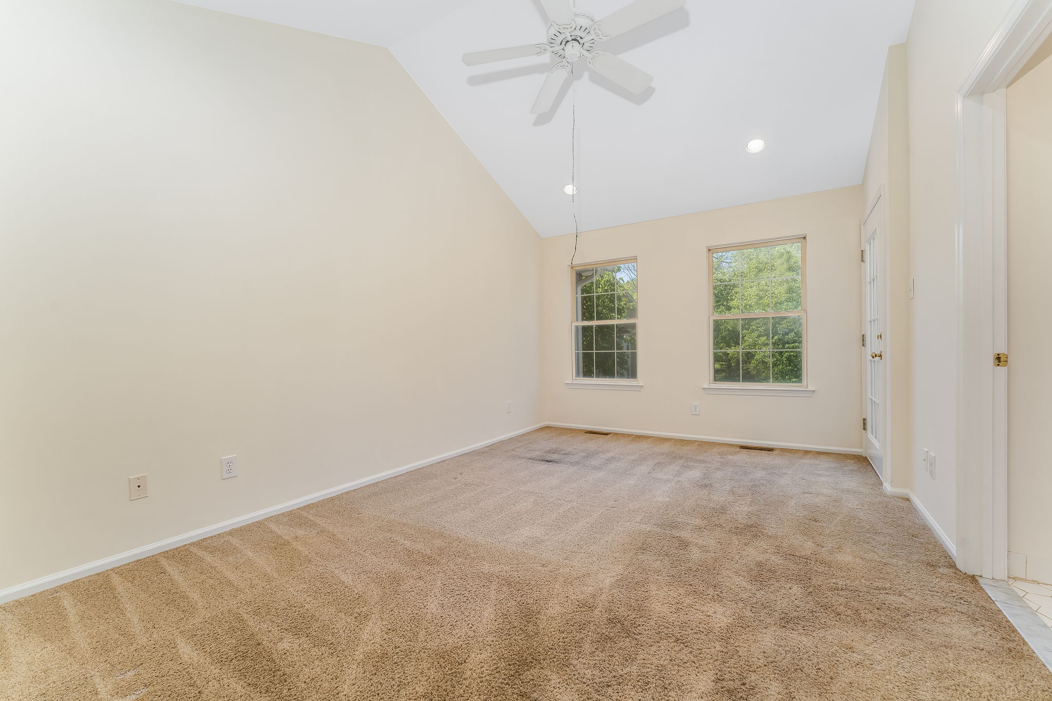 The primary bedroom features a cathedral ceiling, recessed lighting, ceiling fan, walk-in closet, and neutral carpeting, with direct access to a private deck