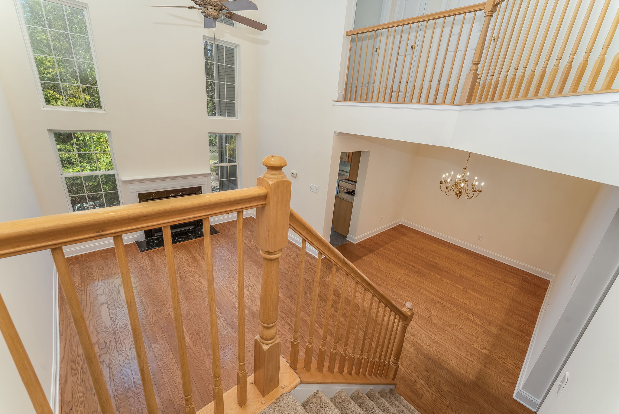 A turned staircase leads to an open balcony with full view of the great room below. Other features include an iron chandelier and carpeted steps and landing.