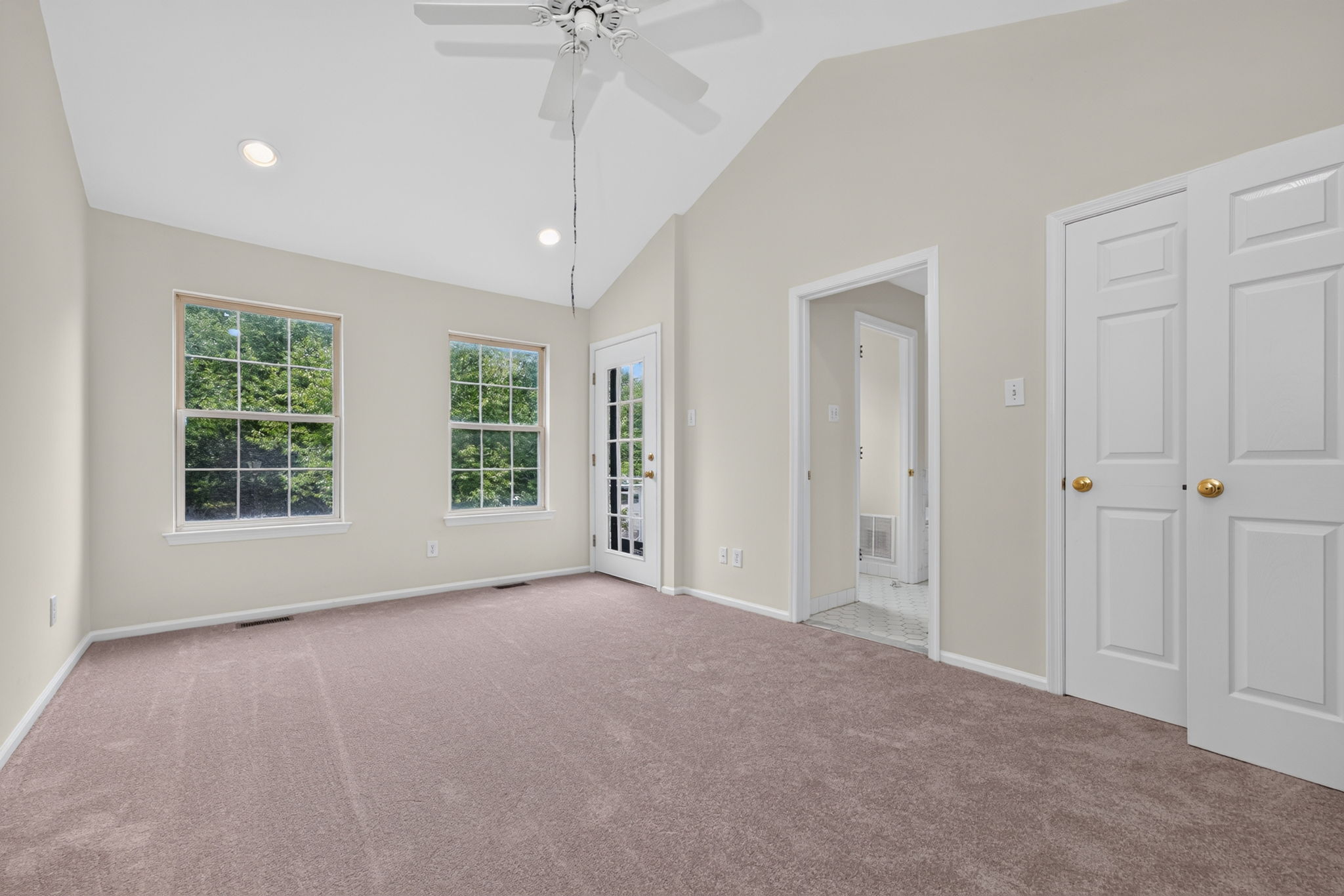 The primary bedroom features a cathedral ceiling, recessed lighting, ceiling fan, walk-in closet, and NEW CARPETING, with direct access to a private deck.