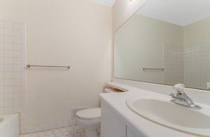 Single basin in white vanity, tub-shower in tile surround, ceramic tile floor. Not Shown-Laundry room with washer and dryer.