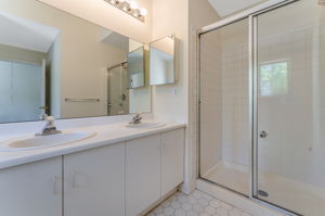 The en suite bath offers a high ceiling, double basins in white vanity, soaking tub and shower in tile surround, ceramic tile floor.