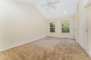The primary bedroom features a cathedral ceiling, recessed lighting, ceiling fan, walk-in closet, and neutral carpeting, with direct access to a private deck