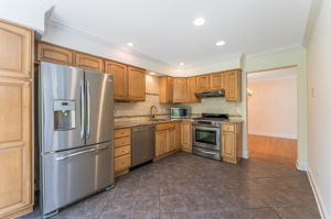 The renovated kitchen features raised-panel cabinetry with soft close drawers and pantry, granite counter tops, ceramic tile backsplash, stainless steel appliances, and ceramic tile floor.